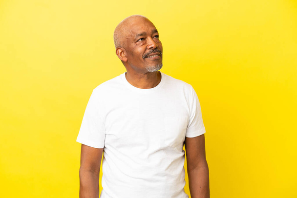 Cuban Senior isolated on yellow background looking to the side and smiling - Zdjęcie, obraz