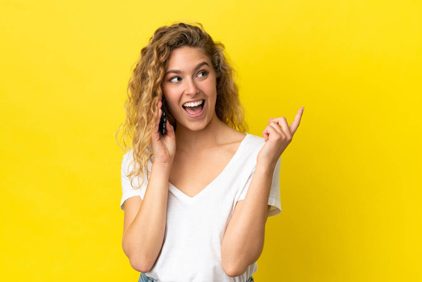 Young blonde woman using mobile phone isolated on yellow background pointing up a great idea - Foto, immagini