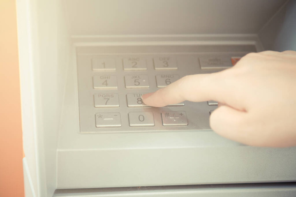 Gros plan de la main entrant le code PIN à la machine ATM pour retirer son argent - Photo, image