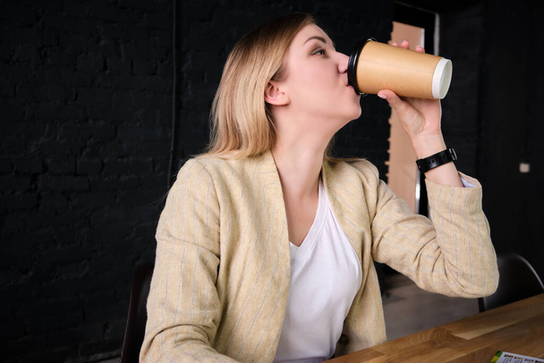 Woman drinks coffee from paper cup - Foto, afbeelding