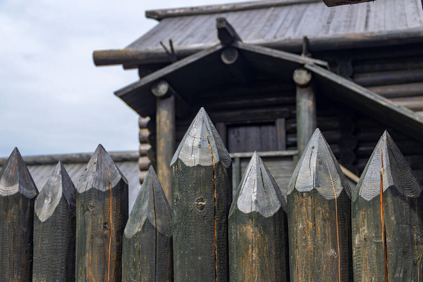 Uma cerca protetora feita de troncos com extremidades superiores afiadas, usada na antiga Rússia para proteger contra inimigos. Tradicional velha construção de madeira russa de casas. - Foto, Imagem
