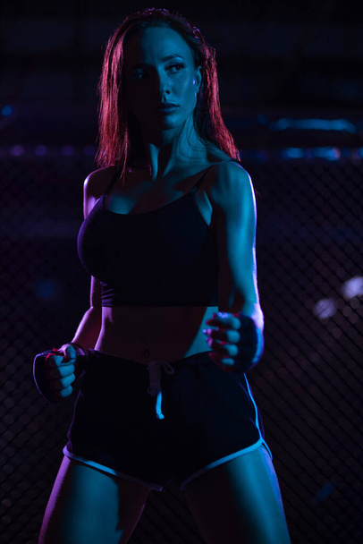 Boxing. Sport concept. Girl fighter on combat without rules in a cage oktobox. Neon photo - Φωτογραφία, εικόνα