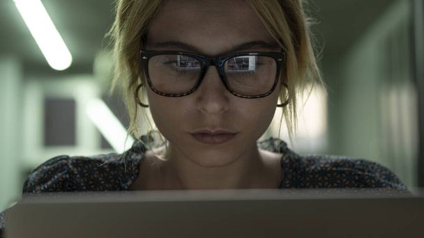 コンピュータとコンピュータの画面ライトを使用している女性はメガネから反射 - 写真・画像
