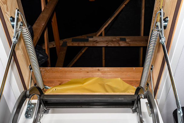 Весенний механизм натяжения, который помогает открыть металлическую лестницу на чердак, размещенный в потолке дома
. - Фото, изображение