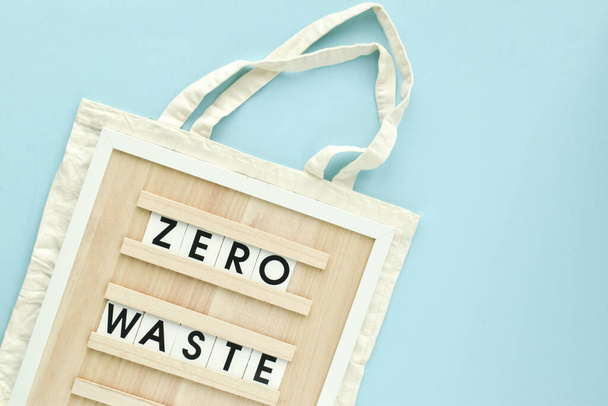 A sign with the inscription Zero waste on a fabric bag on a light blue background. Flat layout, top view, a place to copy. - Fotografie, Obrázek
