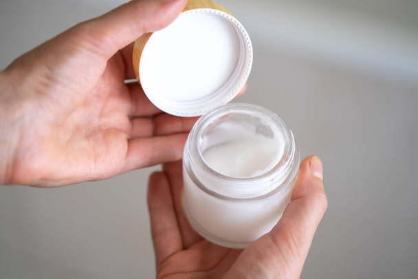Female hands hold a jar of moisturizing cream. - Foto, Imagen