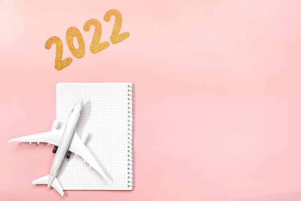 coming 2022 text on pink background. Flat lay design of work desk. with Planning or notebook. New Year for for independent travelers and travel agents. place for text. Copy space - Photo, Image