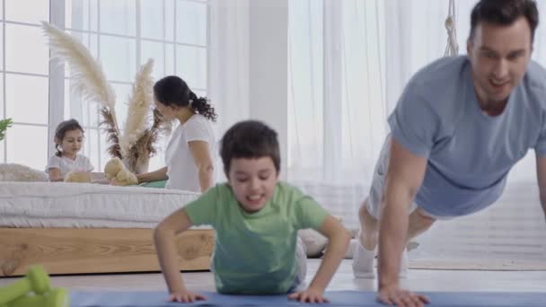 Cuidar padre enseñar hijo a hacer flexiones desde el suelo - Metraje, vídeo