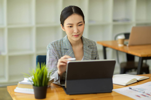 Щаслива молода азіатська бізнес-леді підприємець, використовуючи цифровий планшет, дивлячись на екран, що працює в Інтернеті сидить в кав'ярні
 - Фото, зображення