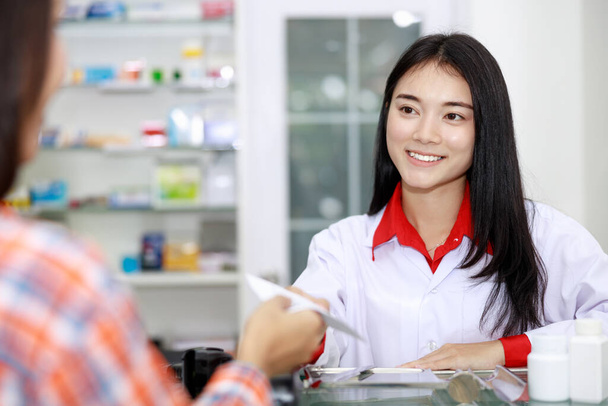 adian kobieta farmaceuta otrzymywać papier list szczegóły leku od pacjentów kobiet w aptece sklep Tajlandia - Zdjęcie, obraz