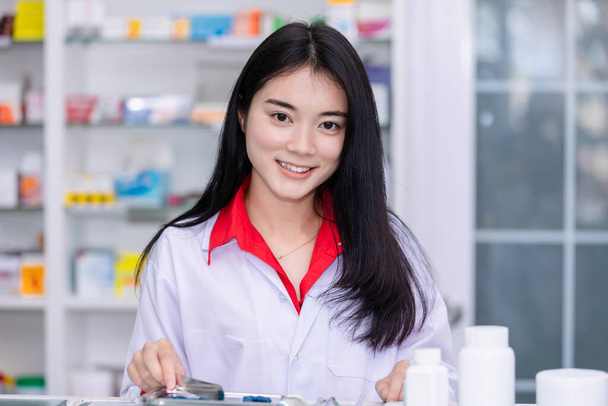 Asiático farmacêutico feminino nublando medicação para pacotes em farmácia Tailândia esporte foco - Foto, Imagem