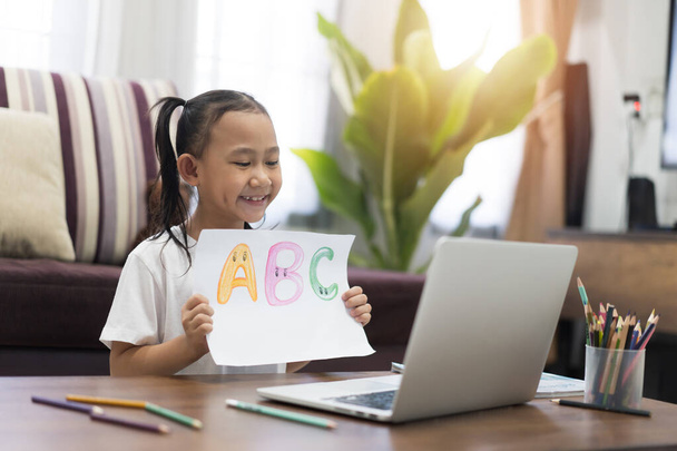 Happy Asian little girl show homework learning using laptop computer virtual internet online, Study From Home idea concept - Fotografie, Obrázek