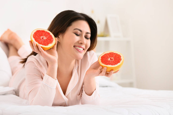 Mañana de joven mujer asiática comiendo toronja en el dormitorio - Foto, Imagen