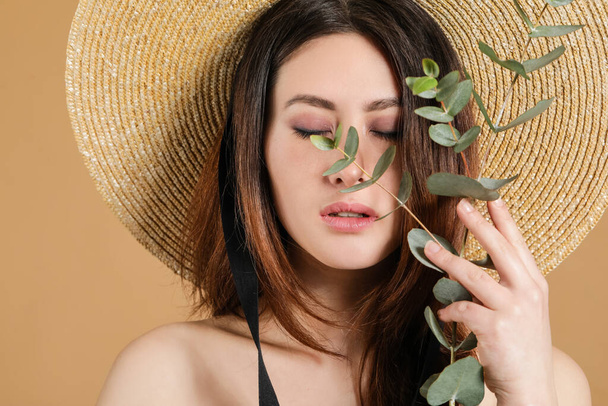 Beautiful young Asian woman with eucalyptus branch on color background - Photo, Image