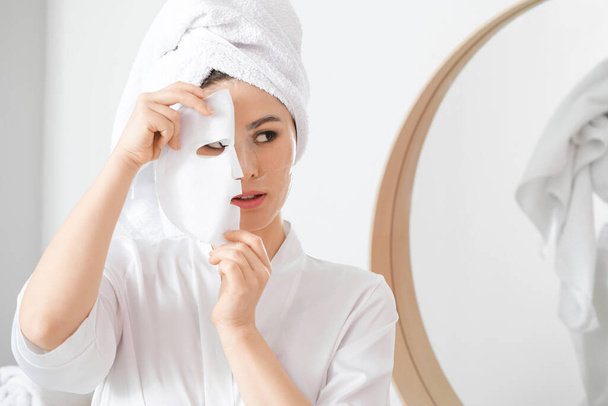 Belle jeune femme asiatique avec feuille masque facial à la maison - Photo, image