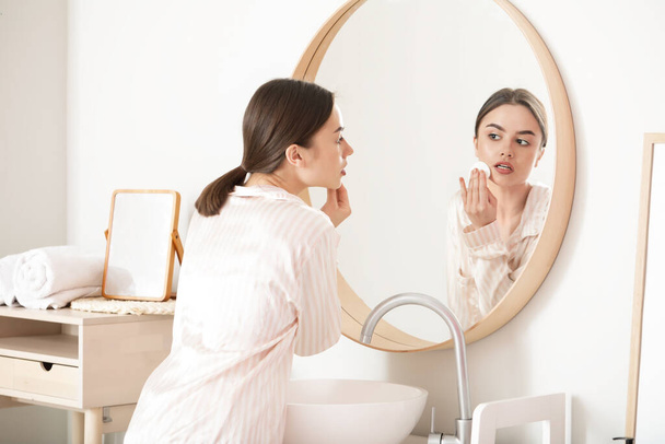 Beautiful young woman removing makeup at home - 写真・画像