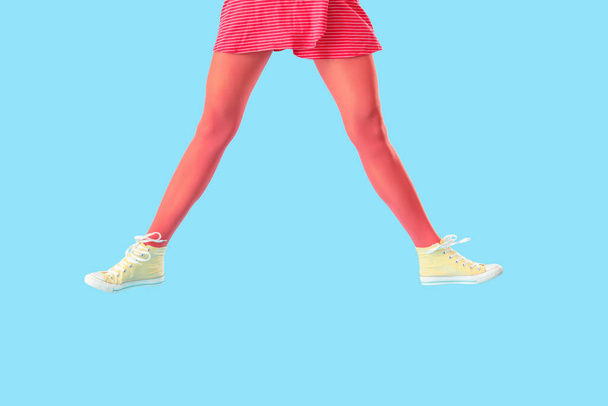 Legs of jumping young woman in tights and casual shoes on color background - Foto, imagen