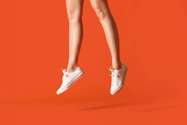 Nogi skaczącej kobiety w luźnych butach na tle koloru - Zdjęcie, obraz