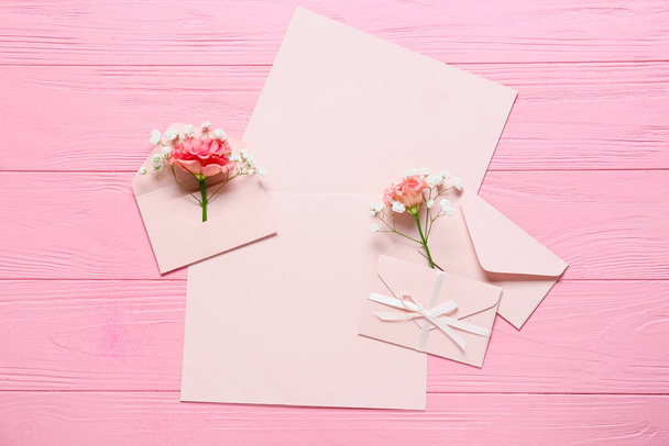 Scheda bianca con buste e fiori su sfondo di legno rosa - Foto, immagini