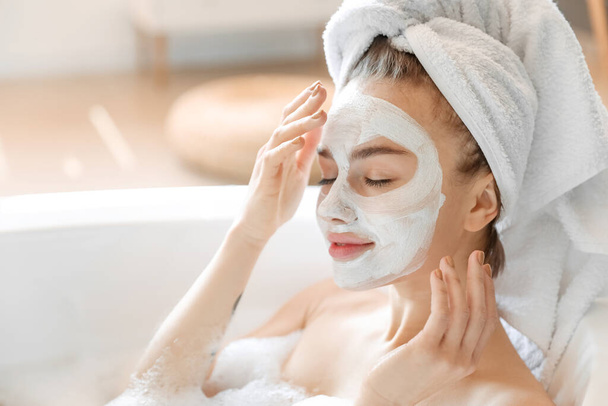 młoda kobieta z maską twarzy biorąc relaksującą kąpiel w domu, zbliżenie - Zdjęcie, obraz