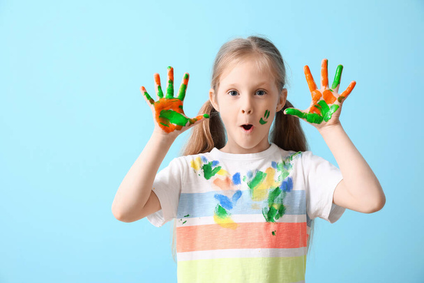 Surprised little girl with hands in  paint on blue background - Photo, Image