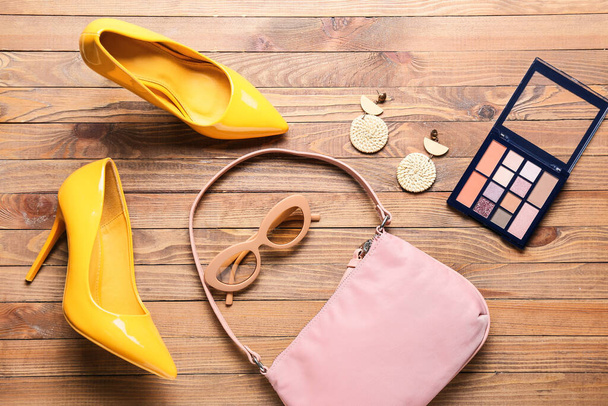 Stijlvolle vrouwelijke accessoires, schoenen en cosmetica op houten ondergrond - Foto, afbeelding
