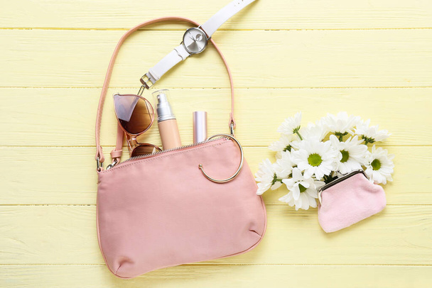Elegante borsa con accessori e bellissimi fiori su sfondo di legno a colori - Foto, immagini