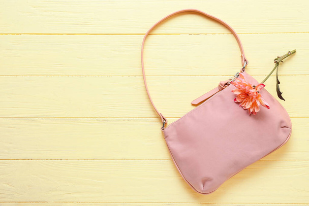 Stylová kabelka a květiny na barevném dřevěném pozadí - Fotografie, Obrázek