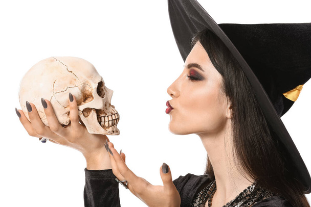 Young witch with human skull on white background - Photo, Image