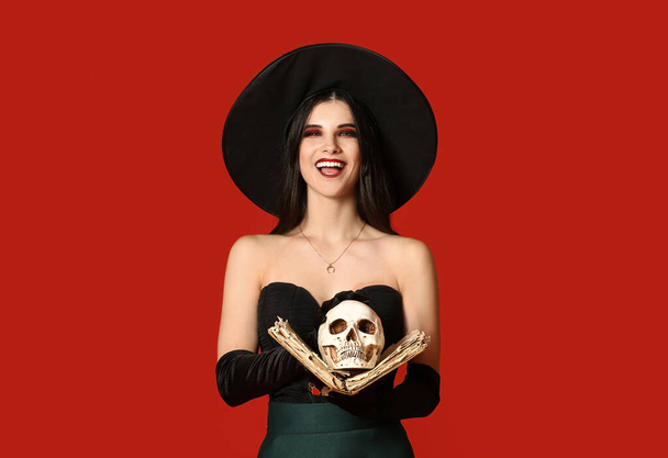Bruxa jovem com crânio e livro de feitiços sobre fundo de cor - Foto, Imagem