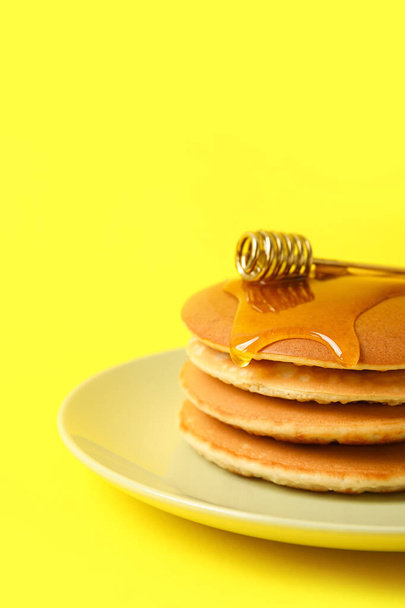 Тарелка вкусных блинчиков с медом на цветном фоне, крупный план - Фото, изображение