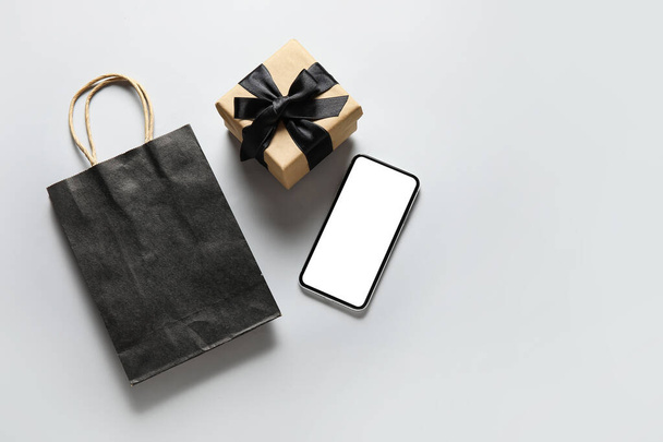 Shopping bag, phone and gift on grey background. Black Friday sale - Photo, Image