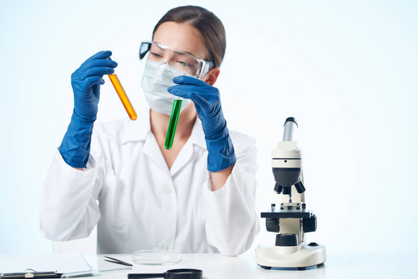 kobieta asystentka laboratoryjna nosząca żółte okulary roztwór chemiczny mikroskop badania biotechnologia - Zdjęcie, obraz