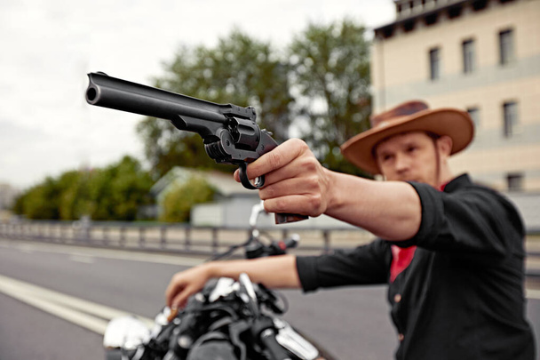 Een maffiaman op de fiets met een pistool. Sportieve motorrijder knappe ruiter man. Achtervolging - Foto, afbeelding