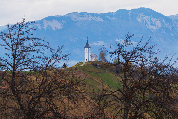 A dombtetőn a csodálatos templom Szent Primus és Szent Felician gyönyörű kilátással a tájra, Jamnik falu, Kranj falu napkeltekor, Triglav Nemzeti Park Szlovéniában - Fotó, kép