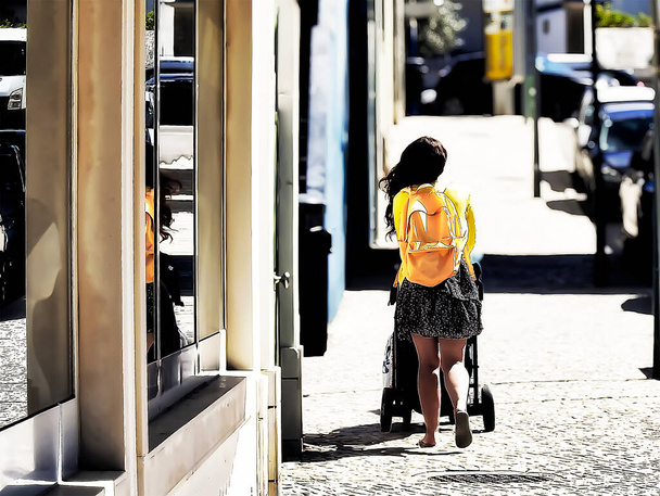 A mother with a pram in town on a cobbled street - Photo, Image