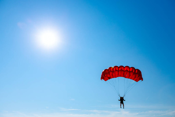 Парашютист медленно спускается с открытым парашютом. Прыжки с парашютом, прыжки с парашютом - Фото, изображение