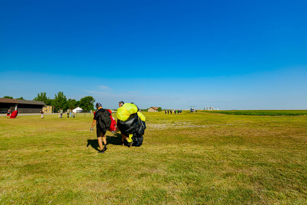 Spadochroniarze przenoszą otwarty spacer spadochronowy nad lotniskiem na Krajowych Mistrzostwach Spadochronowych - Zdjęcie, obraz