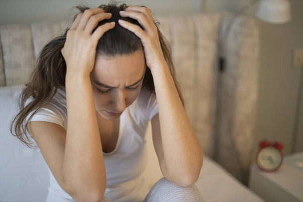 Traurige depressive Frau, die unter Schlaflosigkeit leidet, sitzt im Bett und berührt ihren Kopf, Schlafstörungen oder Stress. - Foto, Bild