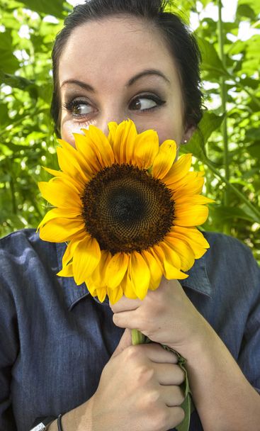 Woman holding sunflower to her face - Foto, immagini