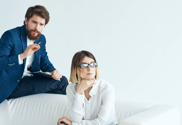 man with woman sitting on a white sofa communication team office work - Photo, Image
