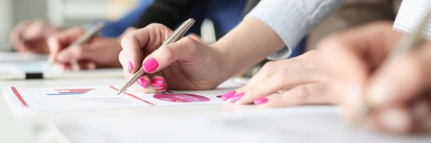 Hands of employees with pens and business graphs with financial indicators - Foto, Imagen