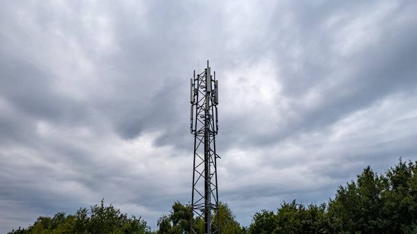 3G, 4G, 5G. Mobiltelefon állomás torony. Kommunikációs rendszer fejlesztése az npn-városi erdős területen sötét viharos szürke égbolttal háttér - Fotó, kép