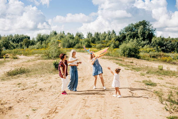 魅力的な少女と彼女の家族は凧を飛んでいます。家族、世代、時間、関係 - 写真・画像