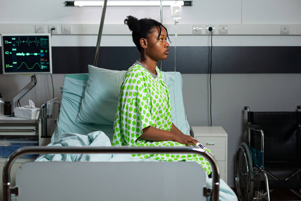 Joven afroamericano sentado en cama de hospital - Foto, Imagen