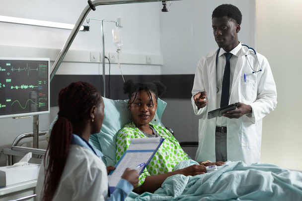 Afroamerikaner spricht Mädchen auf Krankenhausstation an - Foto, Bild