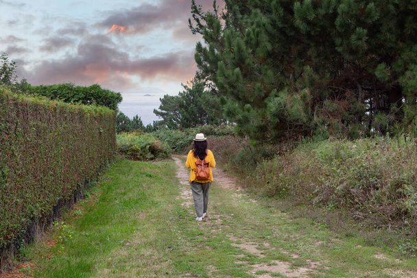 Adult woman with a leather backpack walks down through the path - Photo, Image