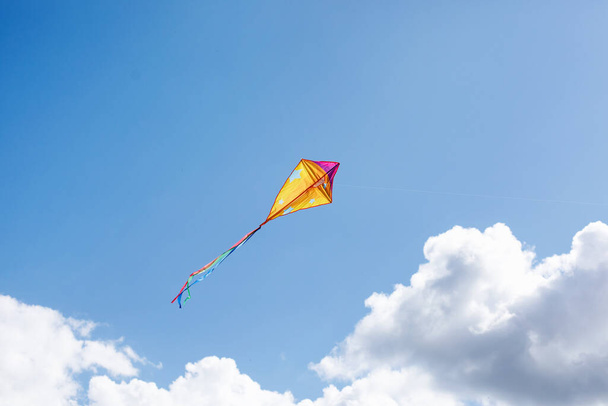 Ένας πολύχρωμος χαρταετός πετάει στον ουρανό - Φωτογραφία, εικόνα
