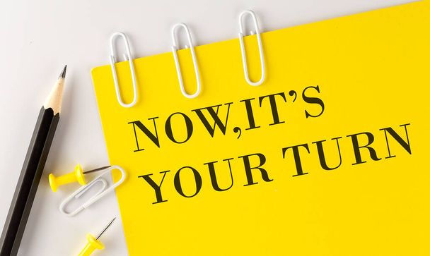 NOW,IT'S YOUR TURN word on the yellow paper with office tools on white background - Photo, Image