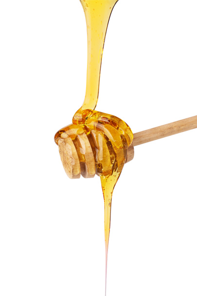 Honey dripping on wooden honey dipper isolated on white background. Organic honey drop. - Foto, Imagen